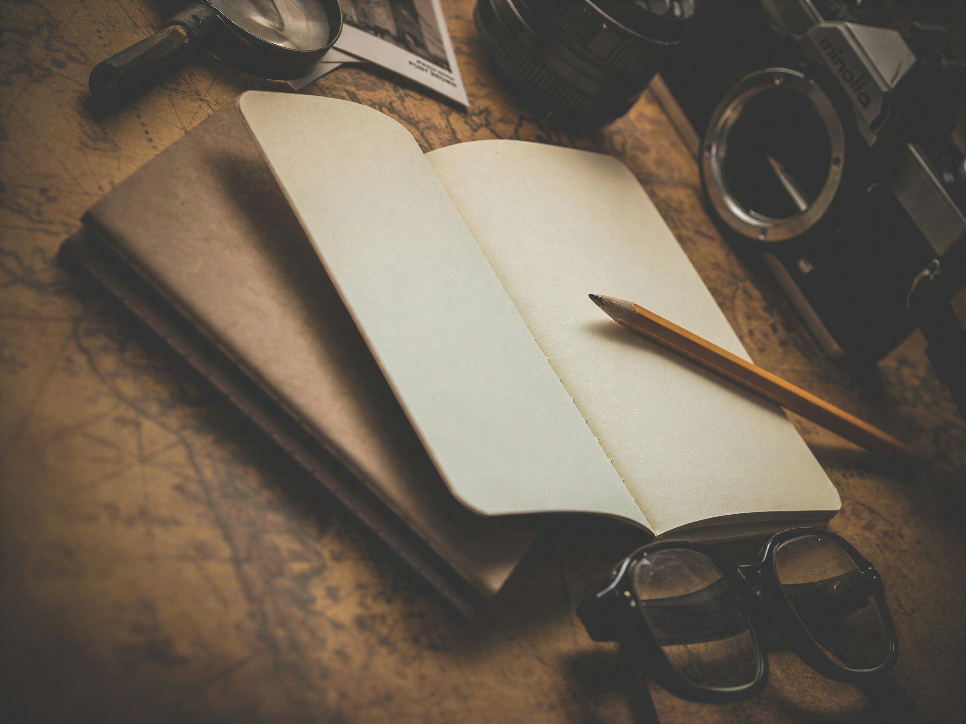 Un cuaderno abierto y un lápiz sobre un escritorio de madera