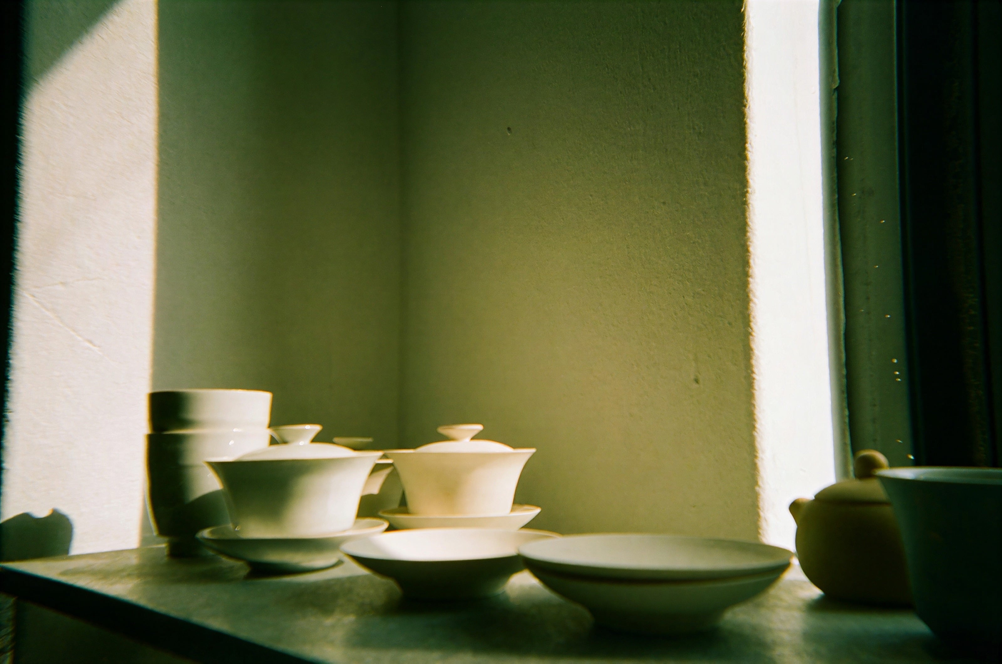 Cuencos de té de cerámica blanca en el alféizar de una ventana soleada