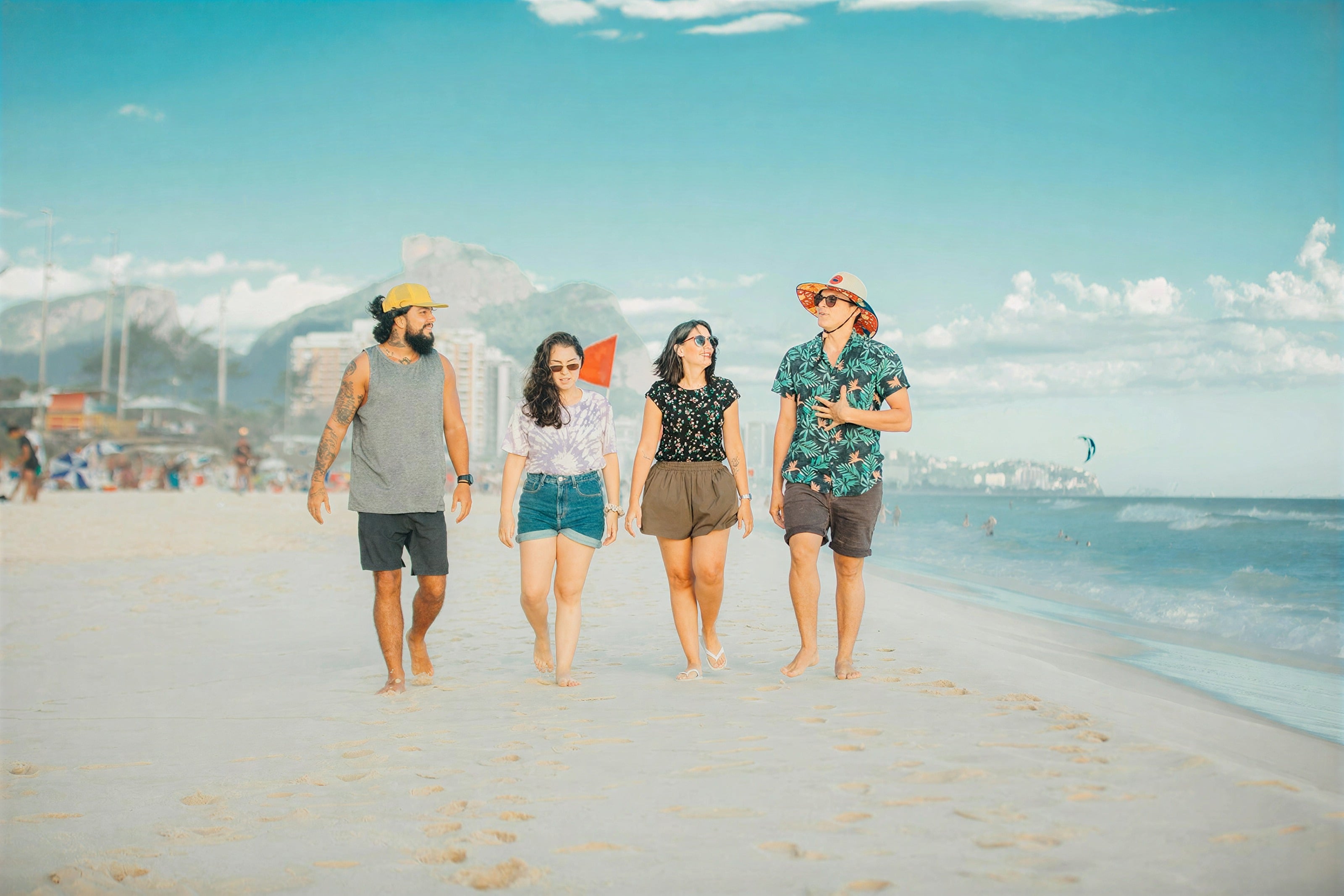 Cuatro amigos caminando descalzos por una playa de arena
