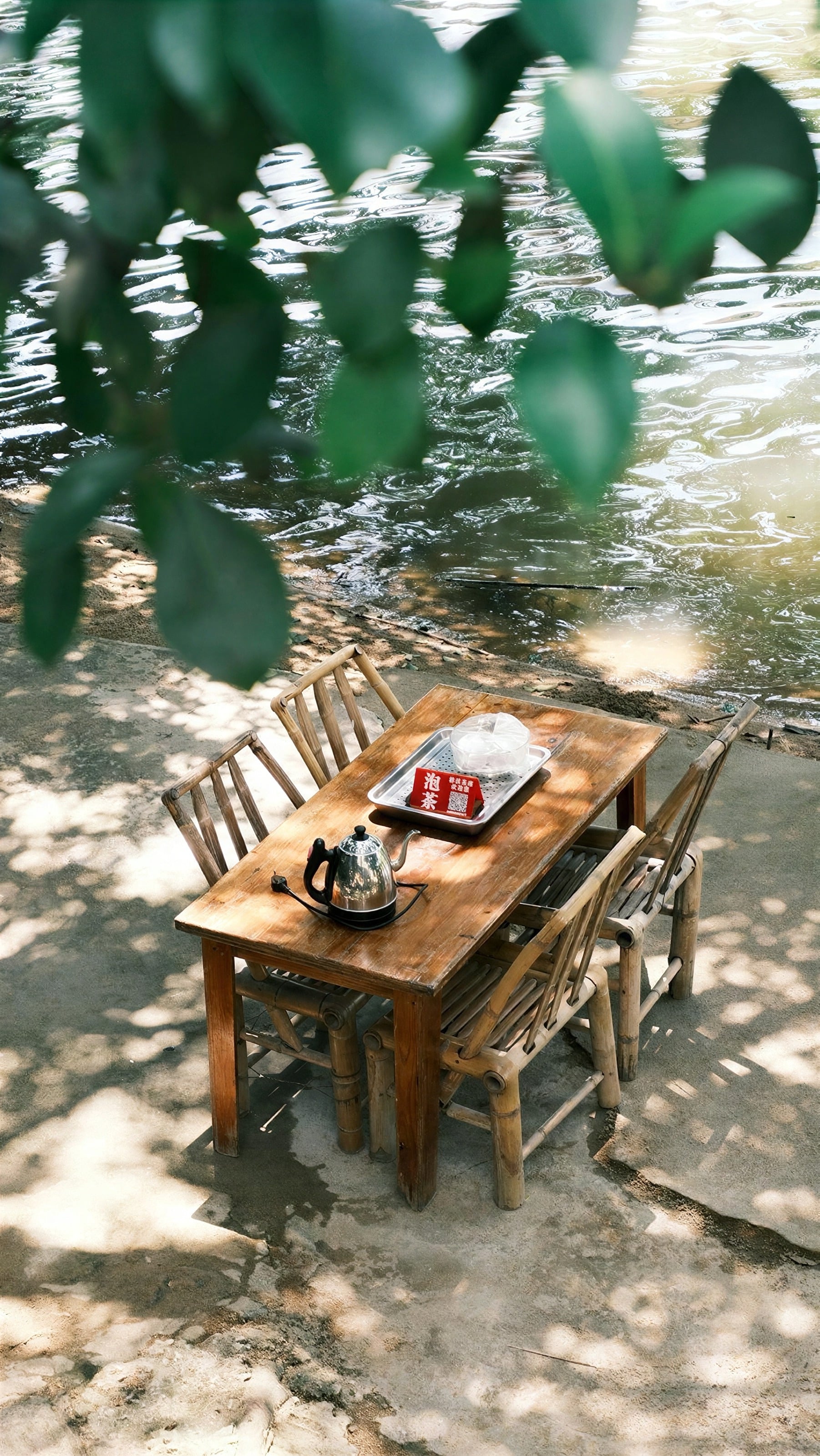 Una mesita de madera preparada para el té a la sombra de los árboles
