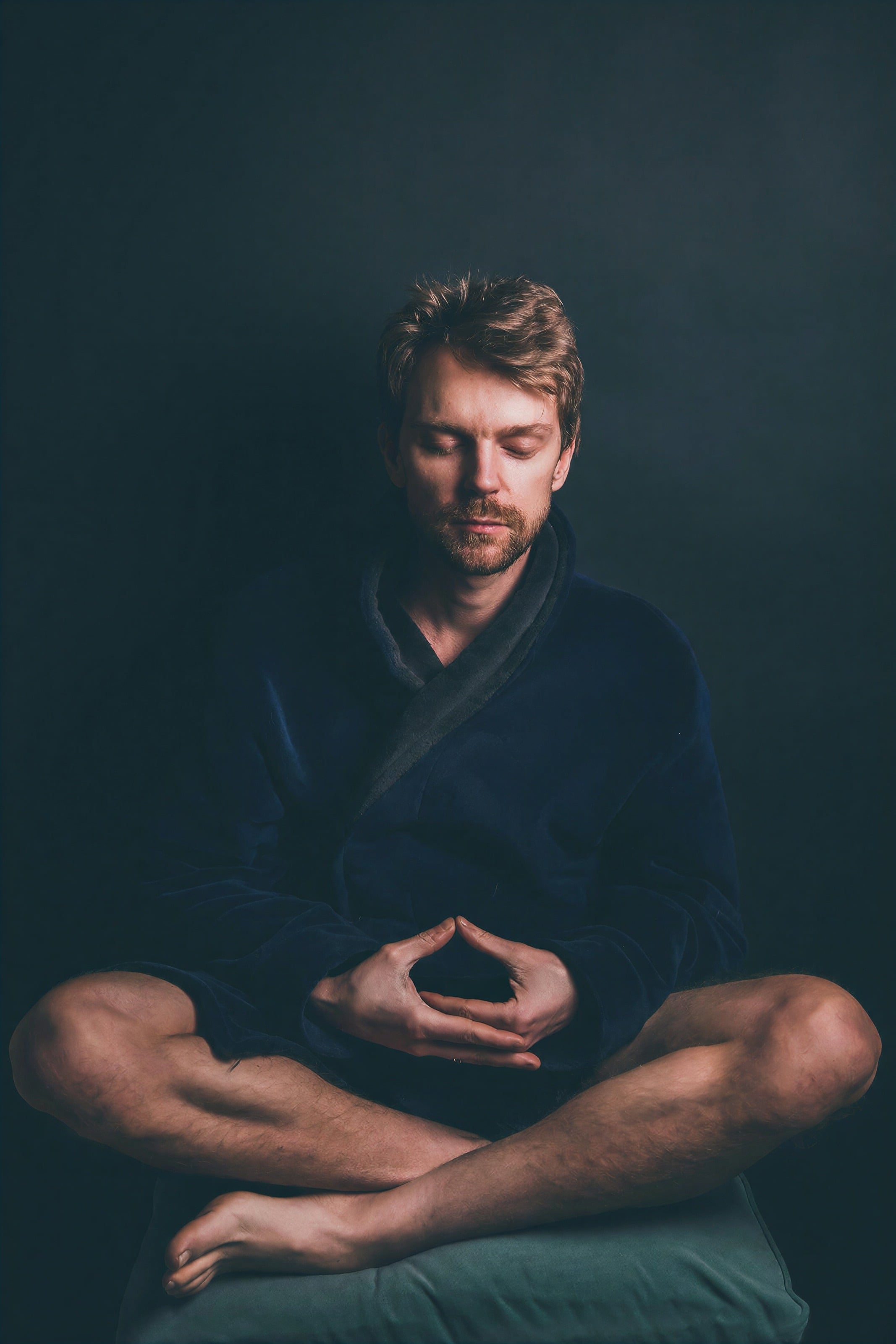 A man meditating cross-legged with his hands resting in his lap