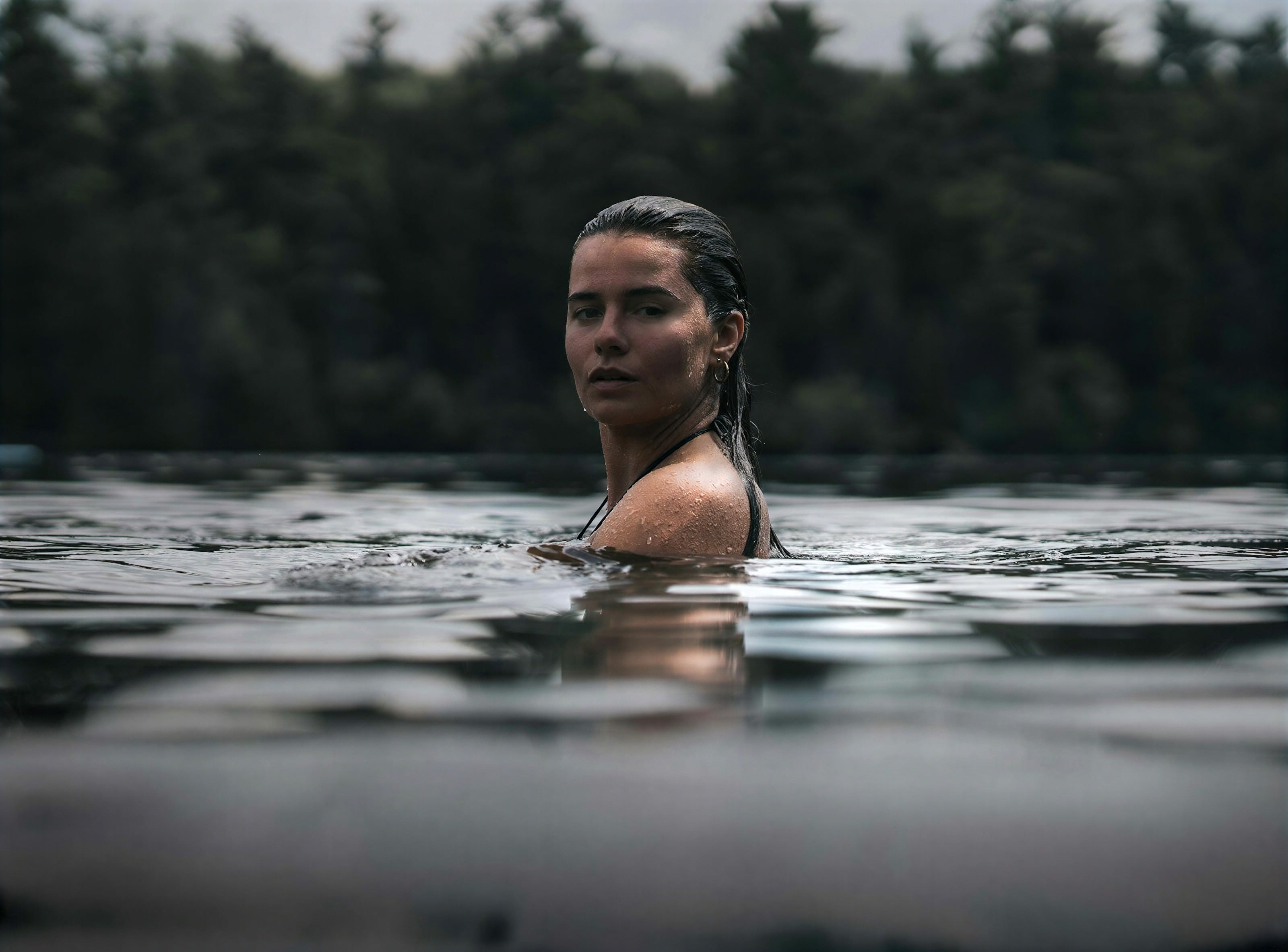 Una mujer nadando en un lago tranquilo rodeado de bosque